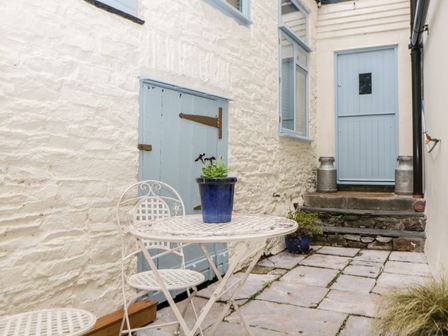 A small outdoor patio with white metal table and chairs blue flower pots two metal milk cans and a pale blue door at The Old Dairy Maker near Millbrook