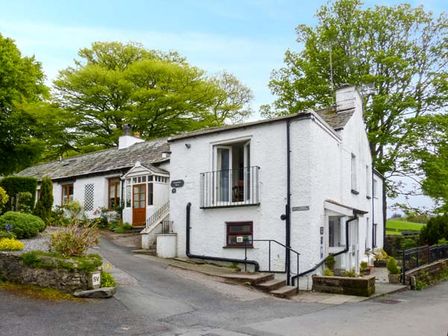 A white house with stone roof and surrounding greenery at Kingfisher Barn in Staveley near Windermere