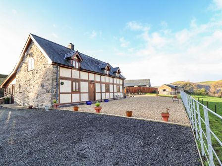 A stone and timber house with gravel and potted plants in the yard at The Old House in Llanidloes