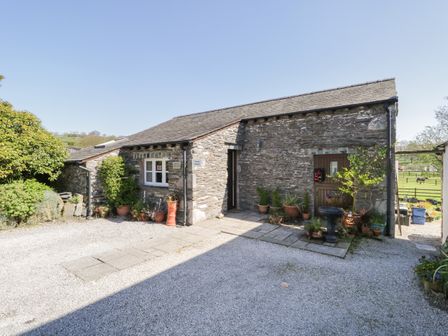 A stone cottage with potted plants outside and a gravel driveway at Topiary Cottage in Ings near Windermere