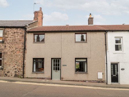 A street view of a row of connected houses with a central door marked number 14 and four windows at York Cottage in Wooler