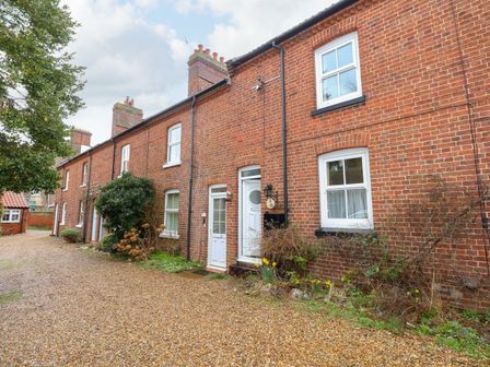 A row of brick terraced houses with white doors and windows and a gravel driveway at 5 Melinda Cottages East Runton near Cromer