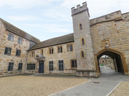 A stone courtyard with a historic building featuring multiple windows and a tall stone tower at Castle House in Taunton