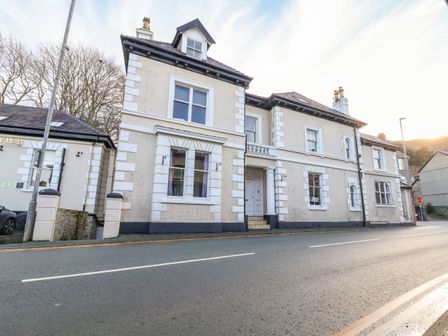 An exterior view of a two story building with white walls and multiple windows along a street at Mountain View in Penmaenmawr
