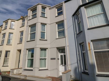 A row of connected multi-story residential buildings with windows and front doors on a street at Y Castell Apartment 1 in Criccieth