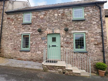 A stone cottage exterior with a green door at Milk Wood Cottage Laugharne
