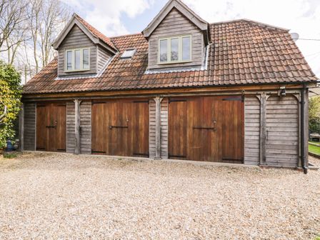 A wooden garage with three brown doors and two dormer windows on a tiled roof at Shephard's Retreat in Charlton Mackrell near Somerton