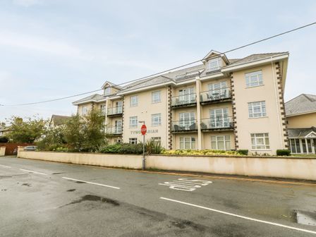 A residential building with balconies and a stop sign on a street at Linksway in Morfa Nefyn