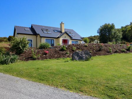 A house with a sloped roof and multiple skylights surrounded by a landscaped garden and grass at Curraha in Lauragh County Kerry