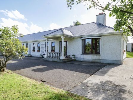 A single story house with a tiled roof and a porch surrounded by trees and a driveway at Belladrihid Cottage Ballysadare near Sligo County Sligo