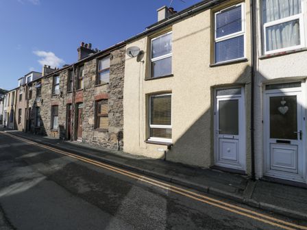 A street view of terraced houses with stone and pebble dash exteriors and white doors at Snowdon View in Llanberis