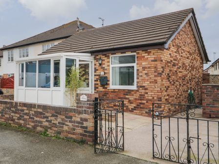 A brick bungalow with a gated entrance and a small enclosed porch at 50A Lloyd Street West in Llandudno