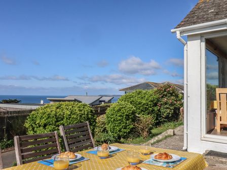 An outdoor dining setup with food and drinks overlooking the sea at Highdown in Bigbury on Sea near Modbury