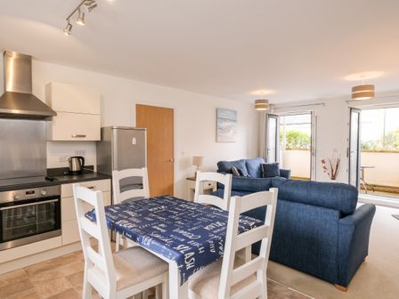A kitchen and living area with a dining table and chairs and blue sofas at Stones Throw in Charlestown