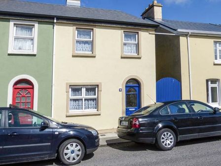 A street view of terraced houses with colored doors and parked cars at High Tide in Belmullet County Mayo