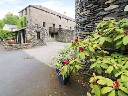 A stone building with potted plants and a pathway at The Hayloft in Lindale