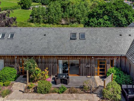 A wooden house with a gray slate roof and patio furniture in a garden at Bramshurst in Upwey near Weymouth