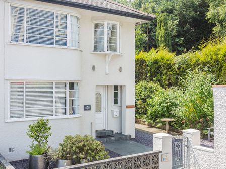 The exterior of a white house with potted plants and a small garden at The Art Deco House in Menai Bridge near Bangor