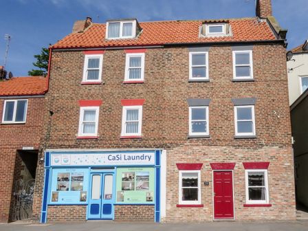 A brick building with CaSi Laundry shop and a red door house at Odd Sock Cottage in Whitby