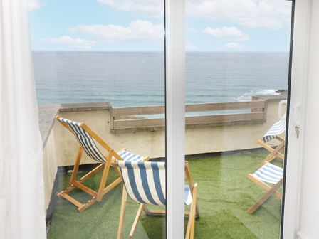 A balcony with deck chairs overlooking the ocean at The Coach House Sennen near St Just