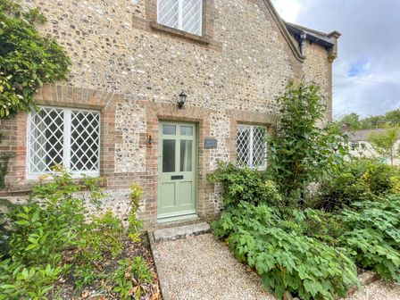 A stone house exterior with green door and lattice windows surrounded by garden at The Old School House in Piddletrenthide