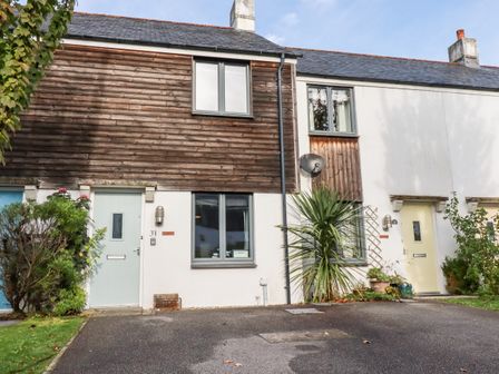 Exterior view of townhouses with wooden and white facades and small front gardens at The Mackerel in Charlestown