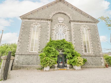 Stone building with arched windows and green plants around the entrance at Capel Mawr Llanrug near Llanberis