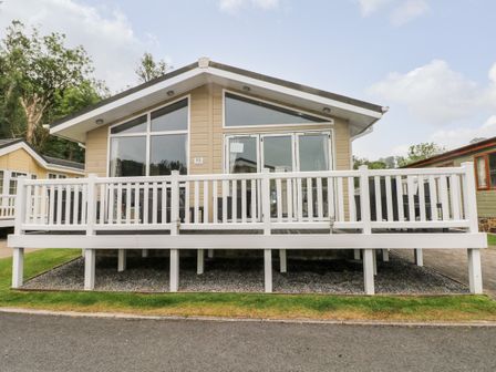 A beige cabin with large windows and white railing on a deck at 95 The Haven Wisemans Bridge near Saundersfoot