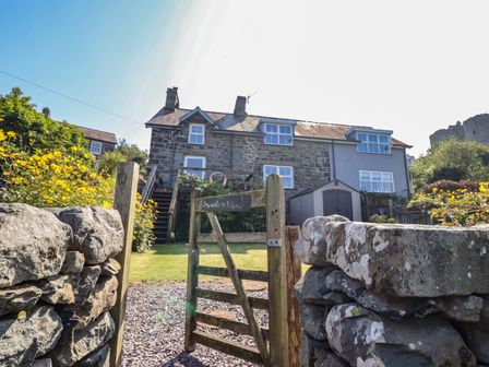 A stone house with wooden gate and stone walls in a garden at Snowdon View in Harlech