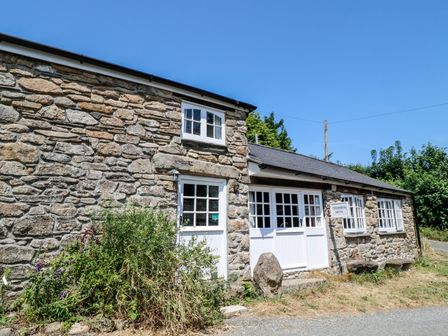 An exterior view of a stone cottage with white doors and windows at Treverbyn Smithy in St Neot