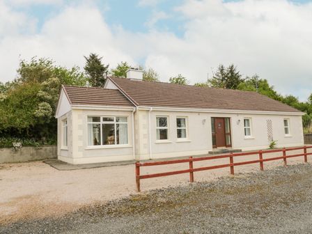A bungalow style house with white walls brown roof and multiple windows surrounded by trees and a gravel driveway at Creeslough View in Creeslough near Glenveagh National Park County Donegal