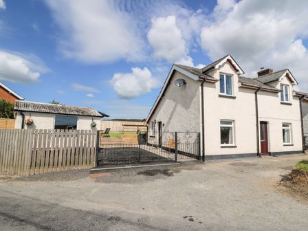 A white two-story house with a driveway and a small outbuilding in a rural setting at Green Cottage in Pant-y-Dwr near Rhayader