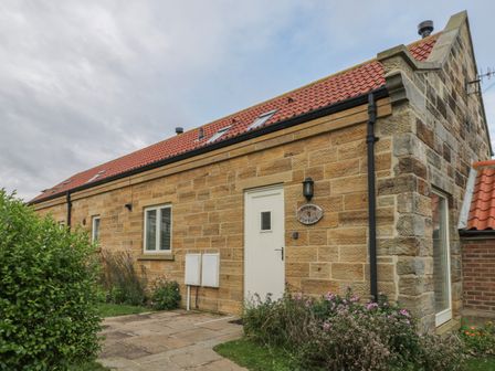 The exterior of a stone cottage with a tiled roof and a garden path at Magpie in Whitby