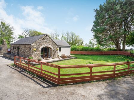A stone cottage with a lawn and wooden fence at Highbury in Spittal near Haverfordwest