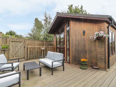 An outdoor seating area with chairs a table and a wooden building at Little Gem Lodge Charlesfield near St Boswells