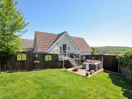 A backyard with lawn, outdoor seating area, and a house with a balcony at Treview in Launceston