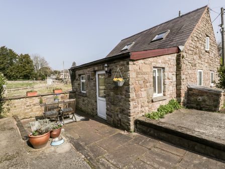 A stone cottage with a small patio and outdoor table and chairs with potted plants at The Pound in Trellech near Monmouth