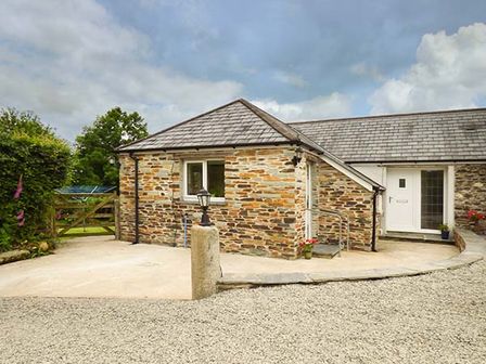 A stone cottage with a tiled roof gravel driveway and wooden gate at Shepherds Rest in Jacobstow near Bude