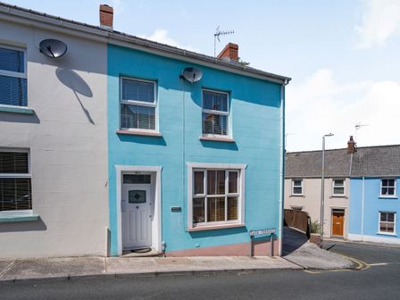 Outer view of a two-story blue and white house with a street sign for Park Terrace and neighboring houses at Dringarth in Tenby