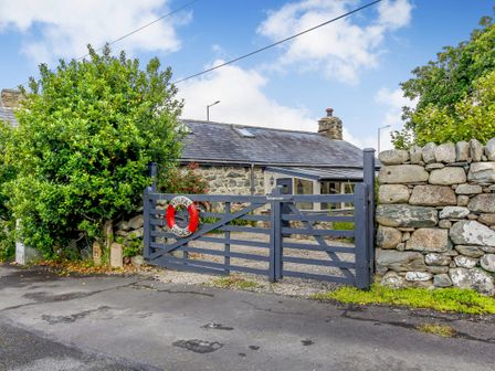 A stone cottage with a dark wooden gate and a life ring attached at Hwylfa'r Groes in Talybont near Barmouth
