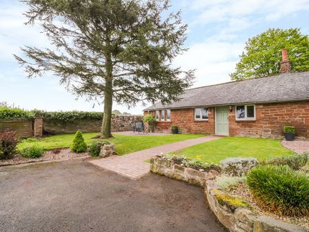 A yard with a tree a path and a stone building at Berrymoor Cottage in Corby Hill