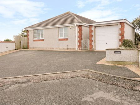 A detached house with a garage a driveway and a small gate at Llewyn Braf in Amlwch