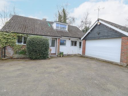 A driveway in front of a house with a tiled roof a garage with a white roller door and a bush near the entrance at Swan Dyke Cottage in Horning near Wroxham
