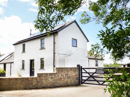 A white house with black windows behind a stone wall and gate at The Old Granary in Spittal