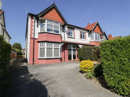 A semidetached house with a driveway and bushes at Hafan Y Mor in Rhos-on-Sea