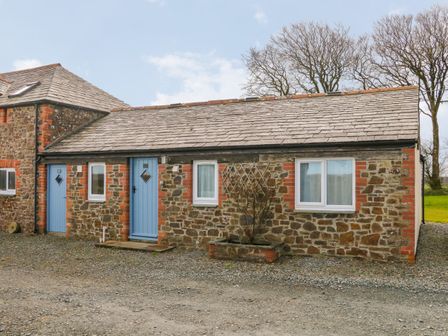 A stone cottage with blue doors and windows with white frames and a small planter in front at The Cottage in Chilsworthy near Holsworthy