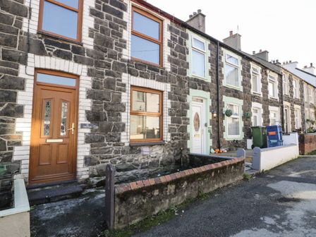 Stone terraced houses with wooden and white doors on a street at Tryfan in Llanberis