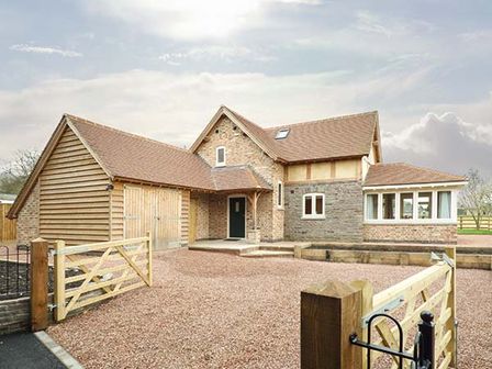 A brick and wood house with a gravel driveway and wooden gate at Rose Cottage in Winforton near Hay-on-Wye