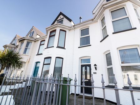 A row of white terraced houses with black and teal doors behind a metal fence at The Salt House in Newquay