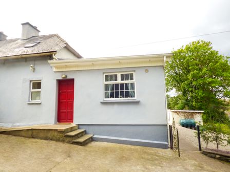 The exterior of a house with a red door grey walls steps and a tree nearby at Berrylane in Enniscorthy County Wexford